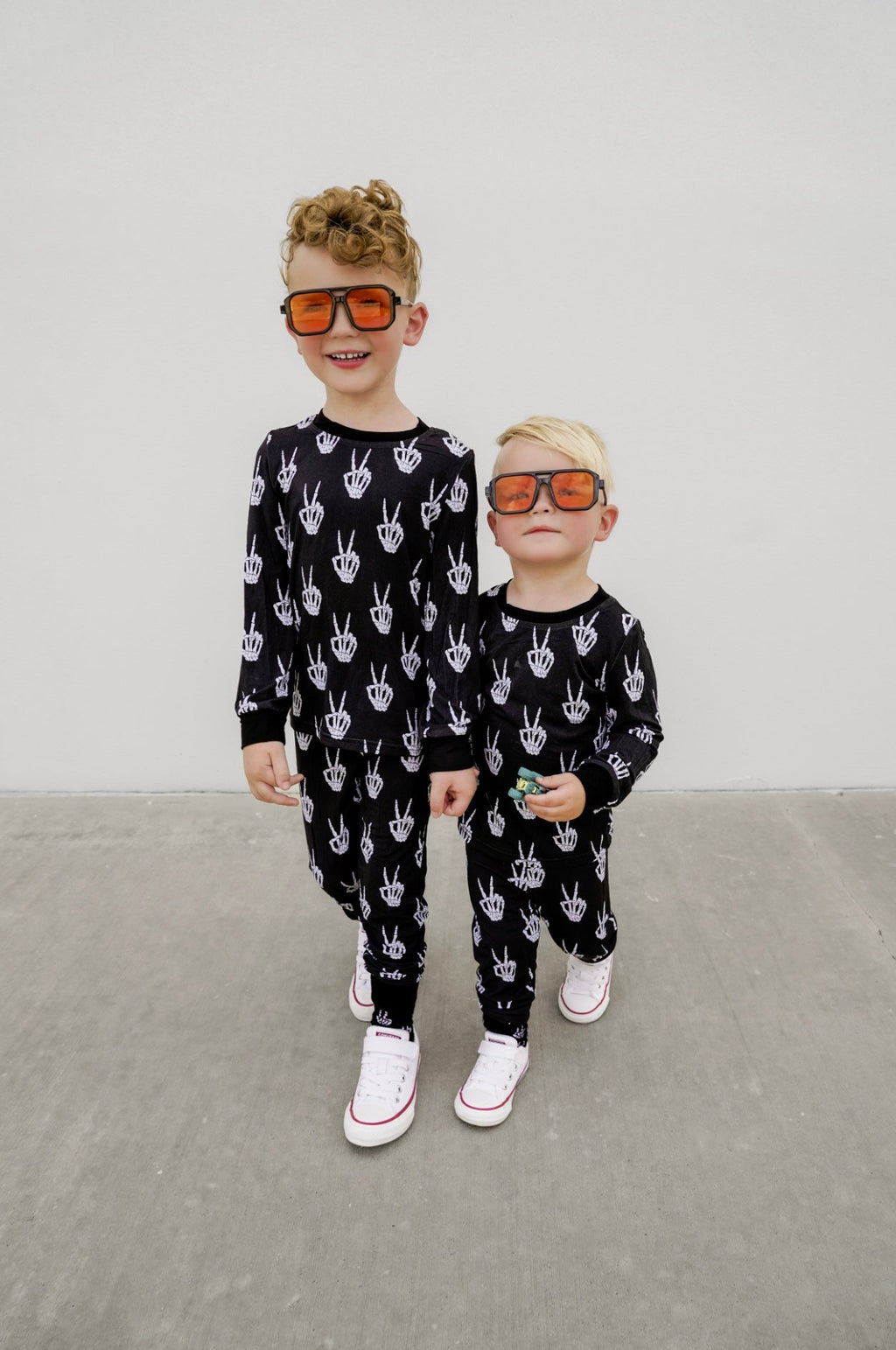 Kids black pajama set with white skeleton-hand pattern, long sleeves and pants.