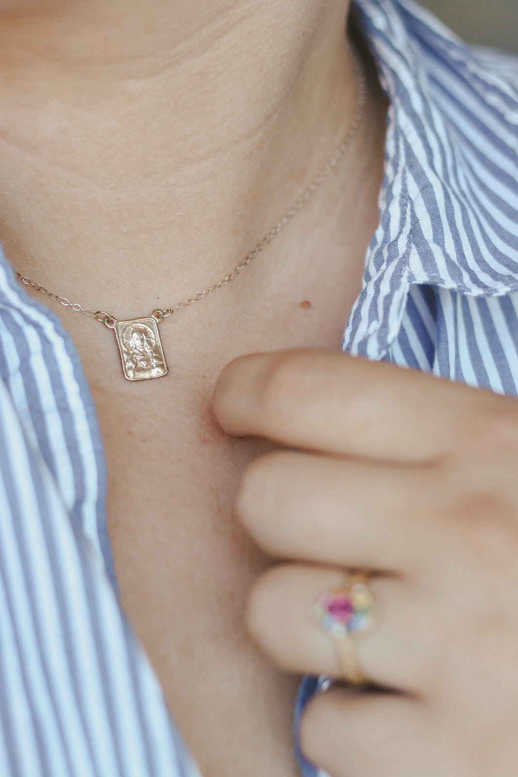 Silver-tone scapular pendant necklace with small square relief charm on fine chain.