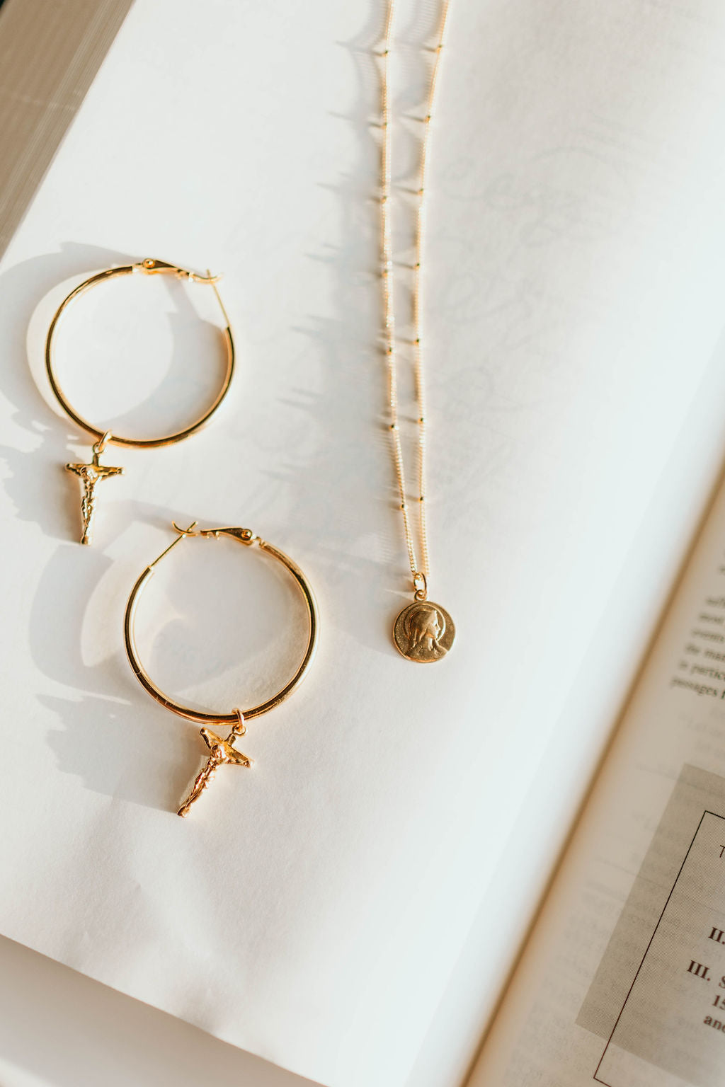Gold-tone crucifix hoop earrings with cross charms, two earrings visible