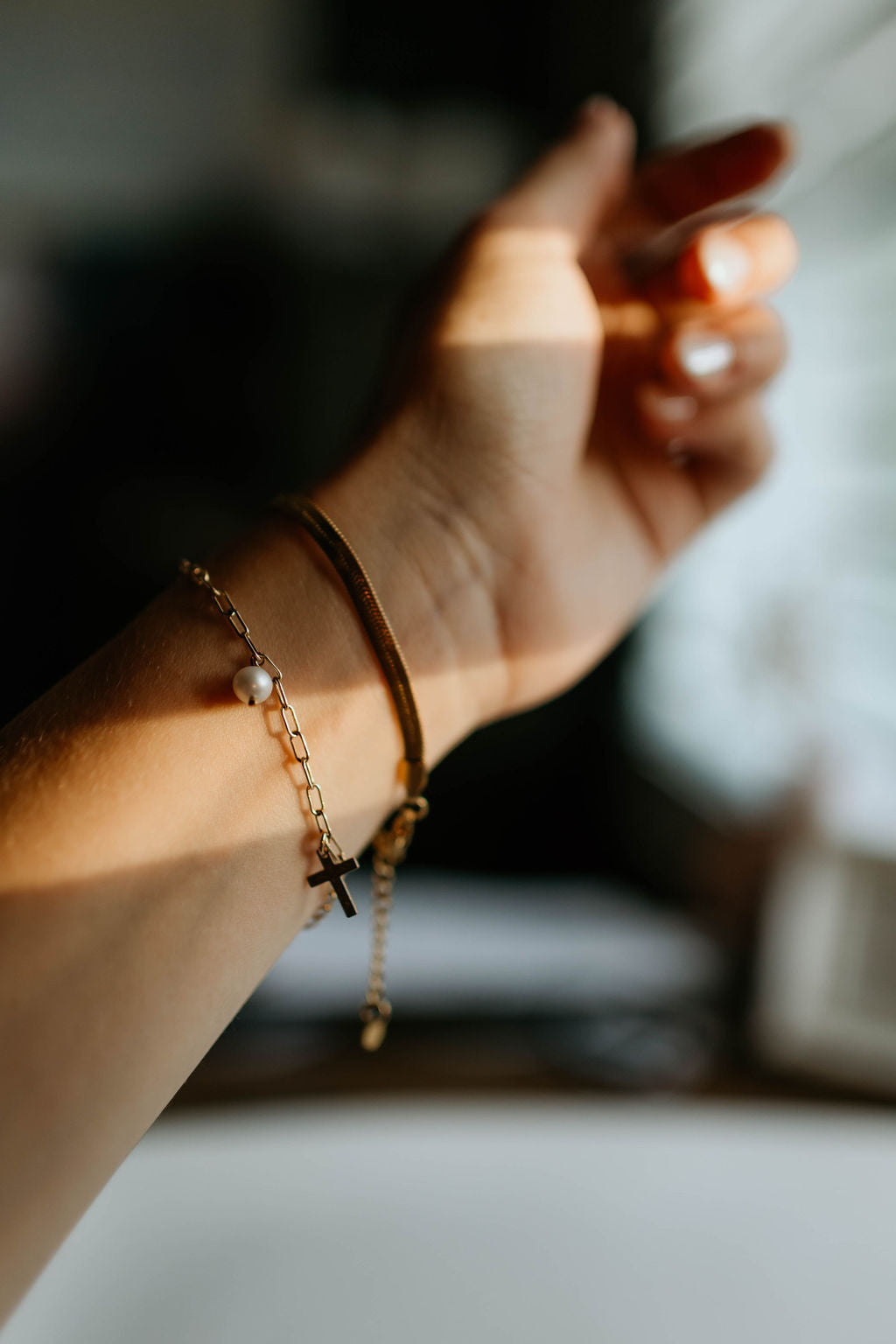 Gold link bracelet with dangling charms and a small cross detail