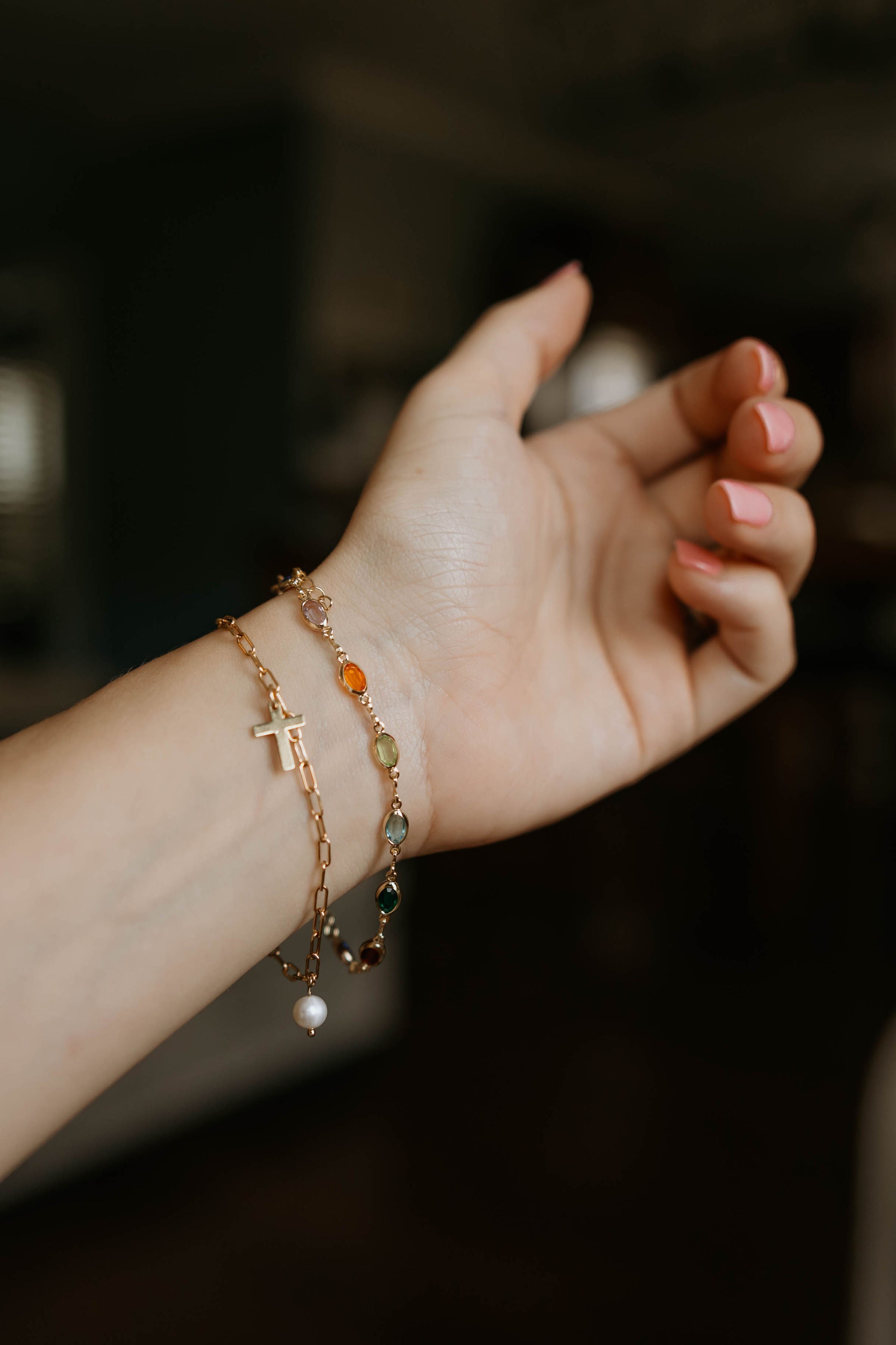 Gold bracelet with a cross charm, pearl beads, and colorful accent beads