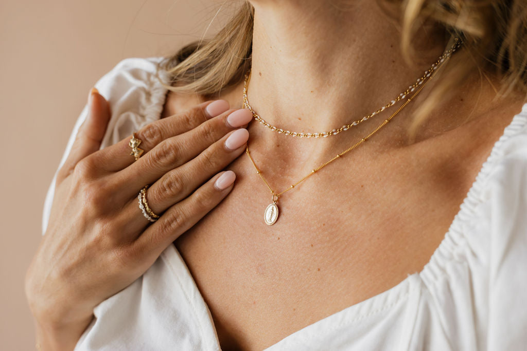 Delicate gold chain necklace with oval medal pendant, close view on neck