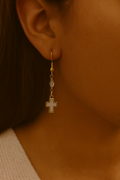Gold cross drop earrings with bead accents, dangling from ear hooks.