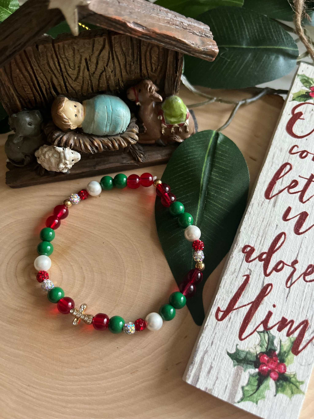 Beaded bracelet with red, green, and white beads and a small silver cross charm