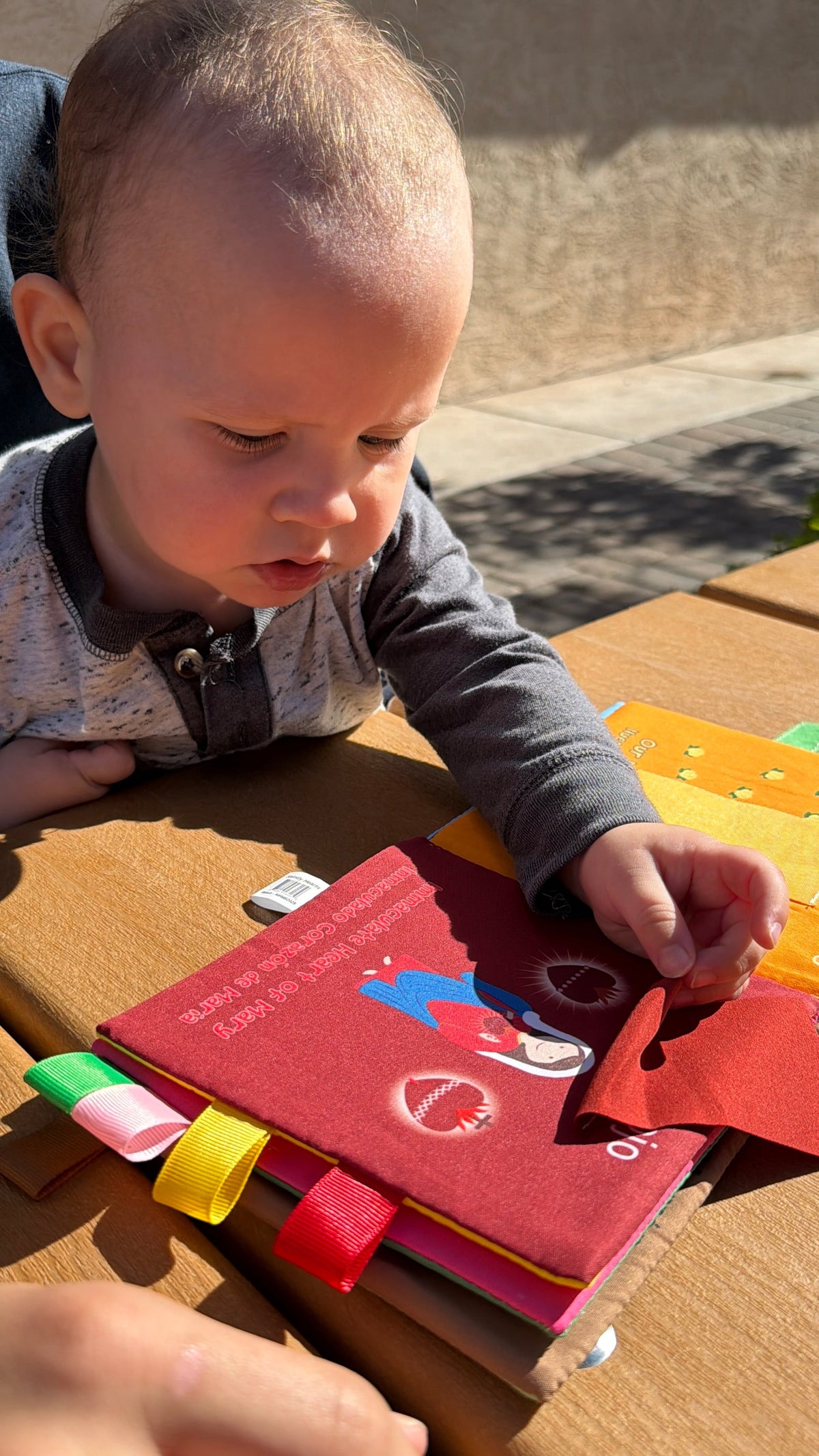 Baby playing with children's board book featuring colorful ribbon tabs