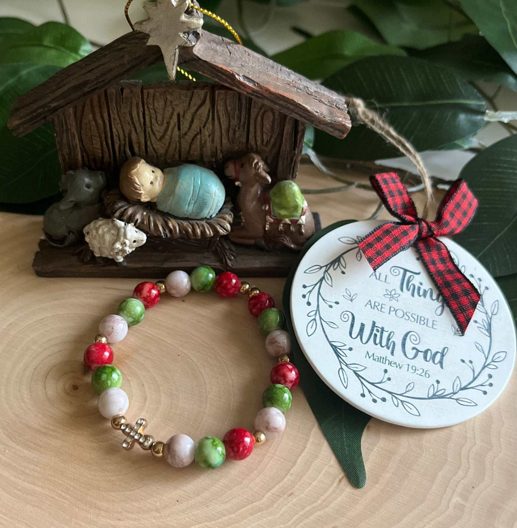 Beaded bracelet with red, green, and white beads and a small silver cross charm