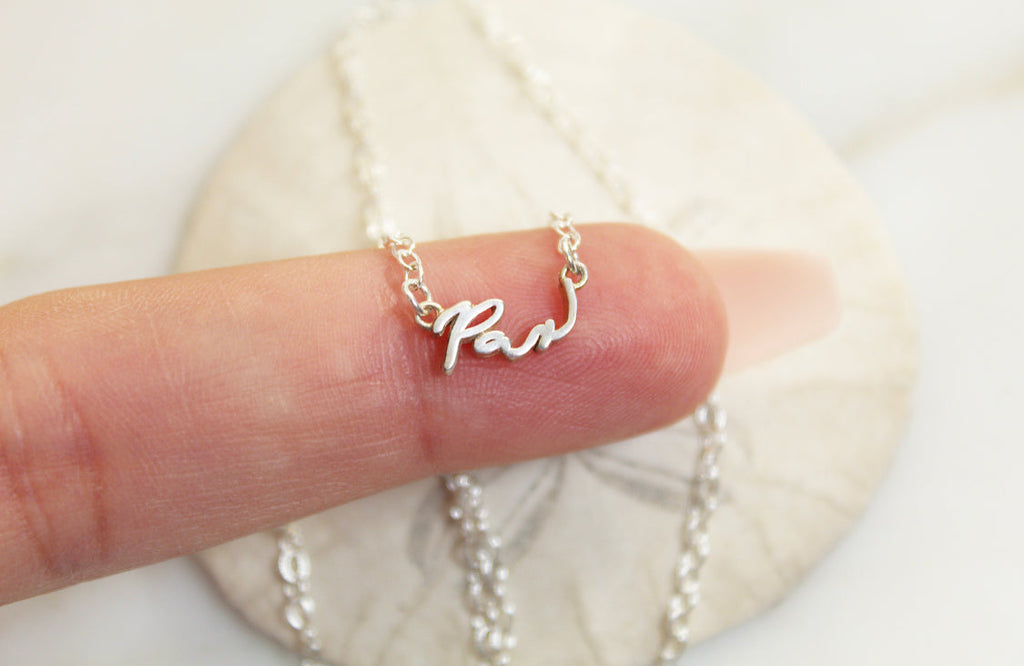 925 sterling silver Pax necklace with cursive Pax pendant held in hand on chain