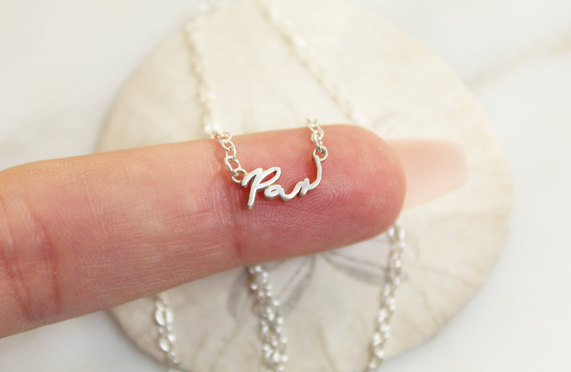 925 sterling silver Pax necklace with cursive Pax pendant held in hand on chain