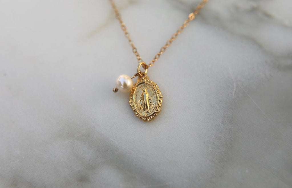 Gold-tone medal necklace with pearl bead and oval filigree pendant on thin chain