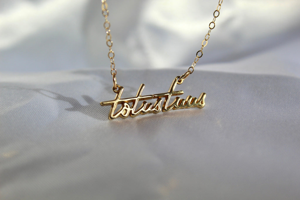 Gold-tone script pendant necklace with chain and pendant centered