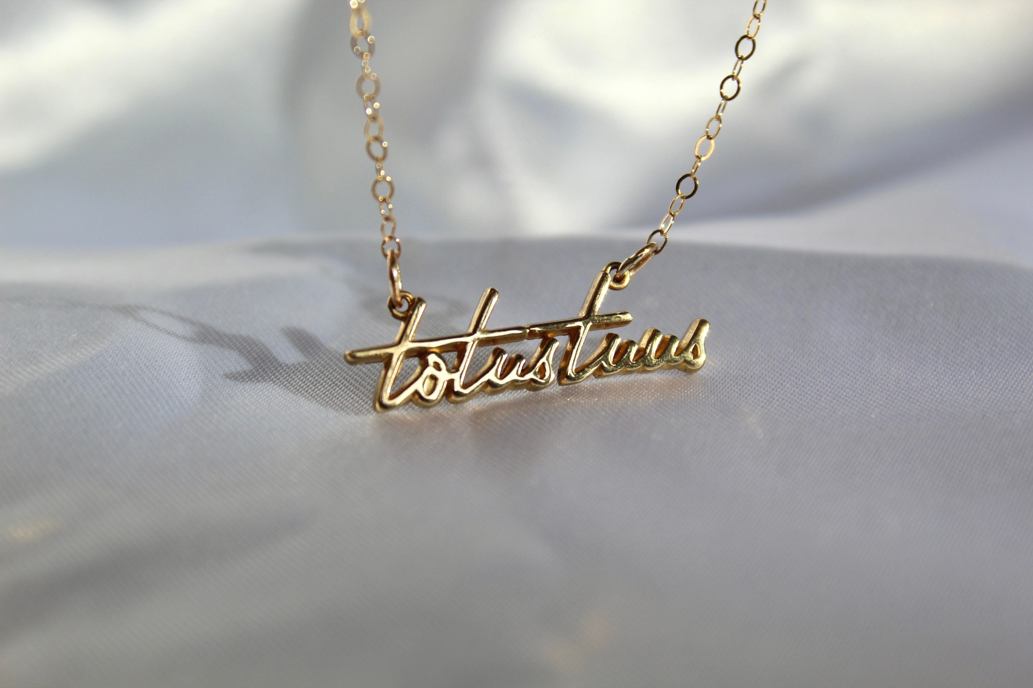 Gold-tone script pendant necklace with chain and pendant centered