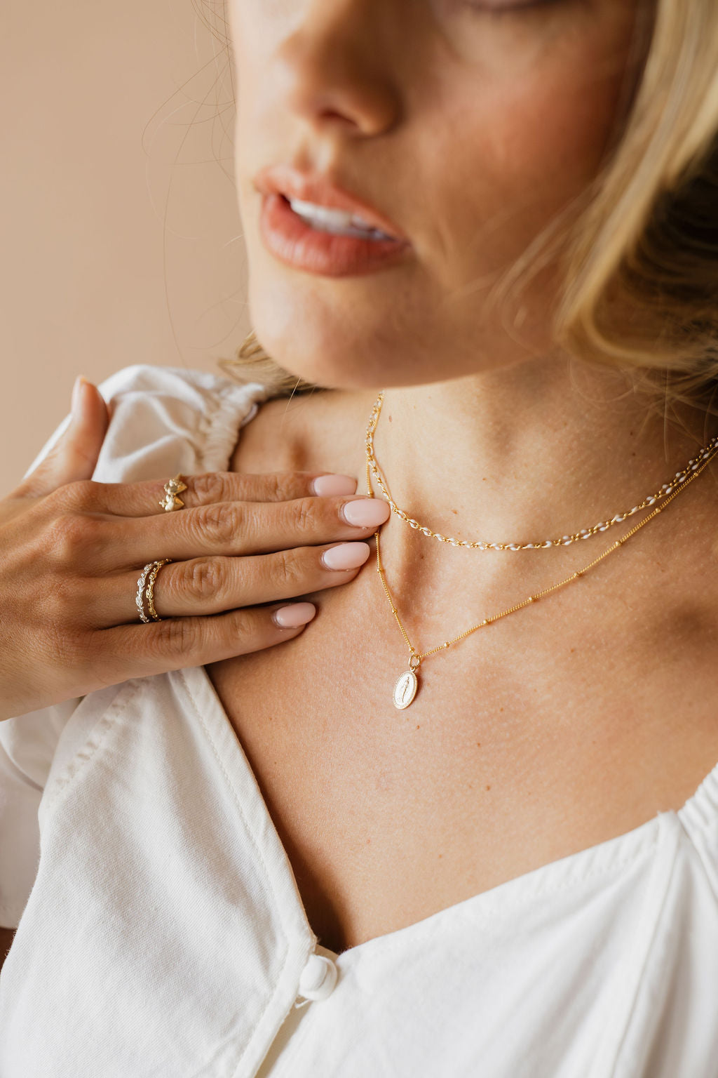 Gold chain necklace with small oval medal pendant near the neckline