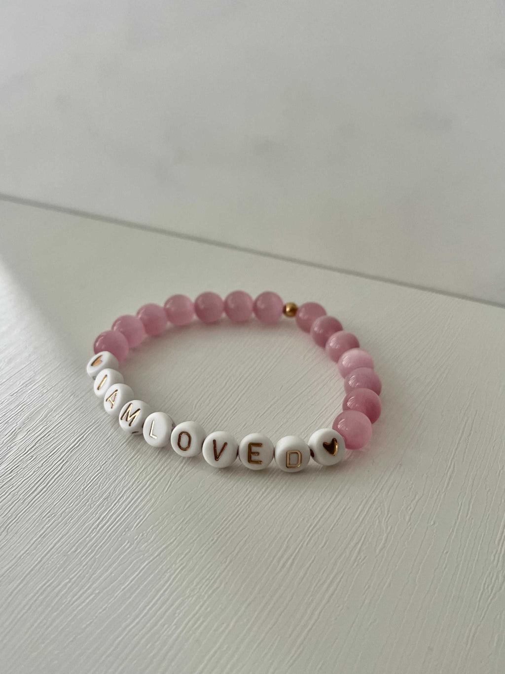 Pink beaded bracelet with 'I AM LOVED' letter beads