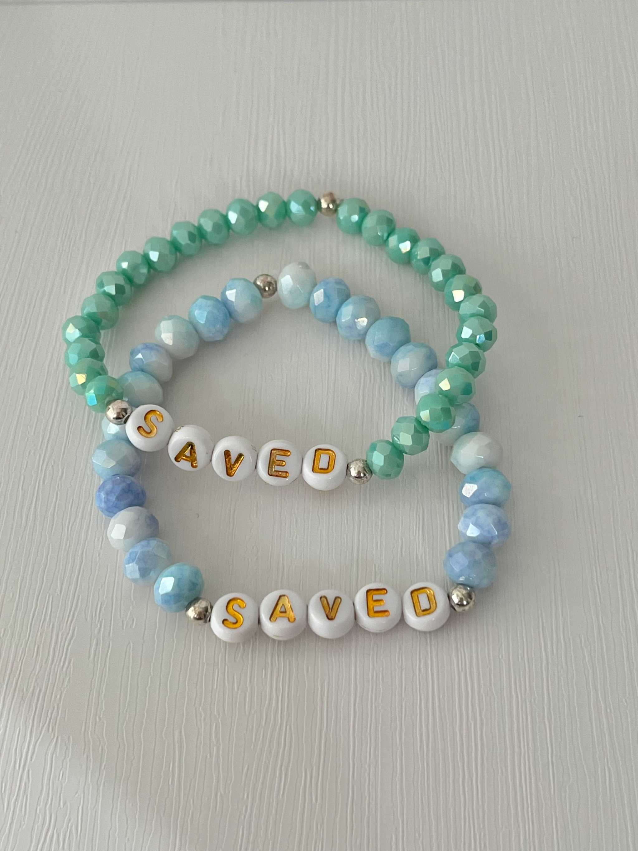 Mint and light blue beaded bracelets overlapping, with 'SAVED' letter beads
