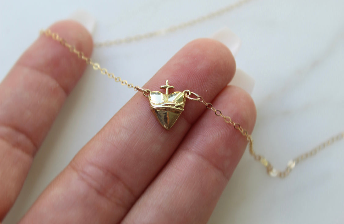 Gold-tone heart pendant necklace with crown and cross charm on thin chain