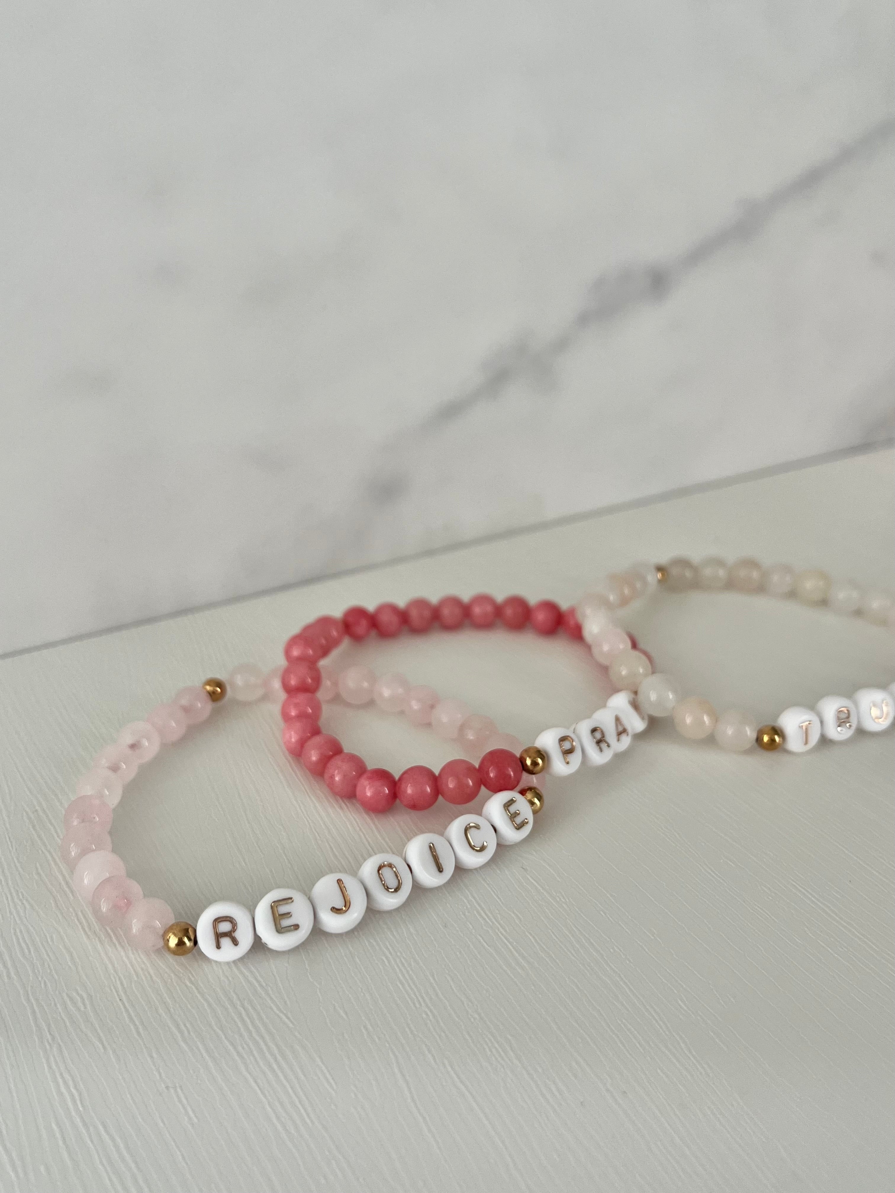 Stacked beaded bracelets with REJOICE and PRAY letter beads, gold tone accents