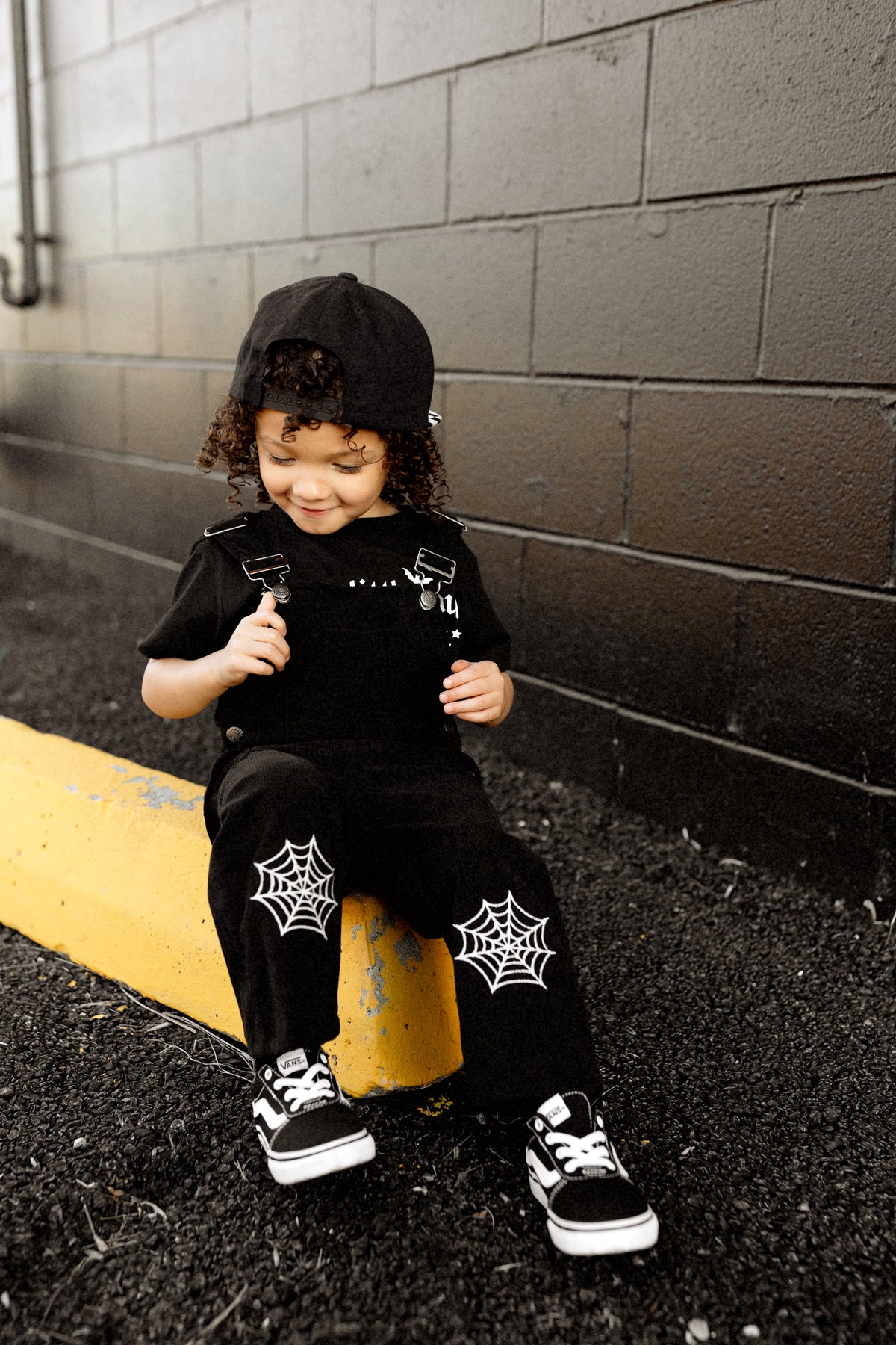 Black spiderweb overalls with shoulder straps, front bib, and web prints on pants.