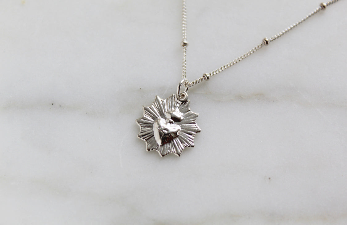 Sterling silver heart pendant necklace with scalloped details on a chain