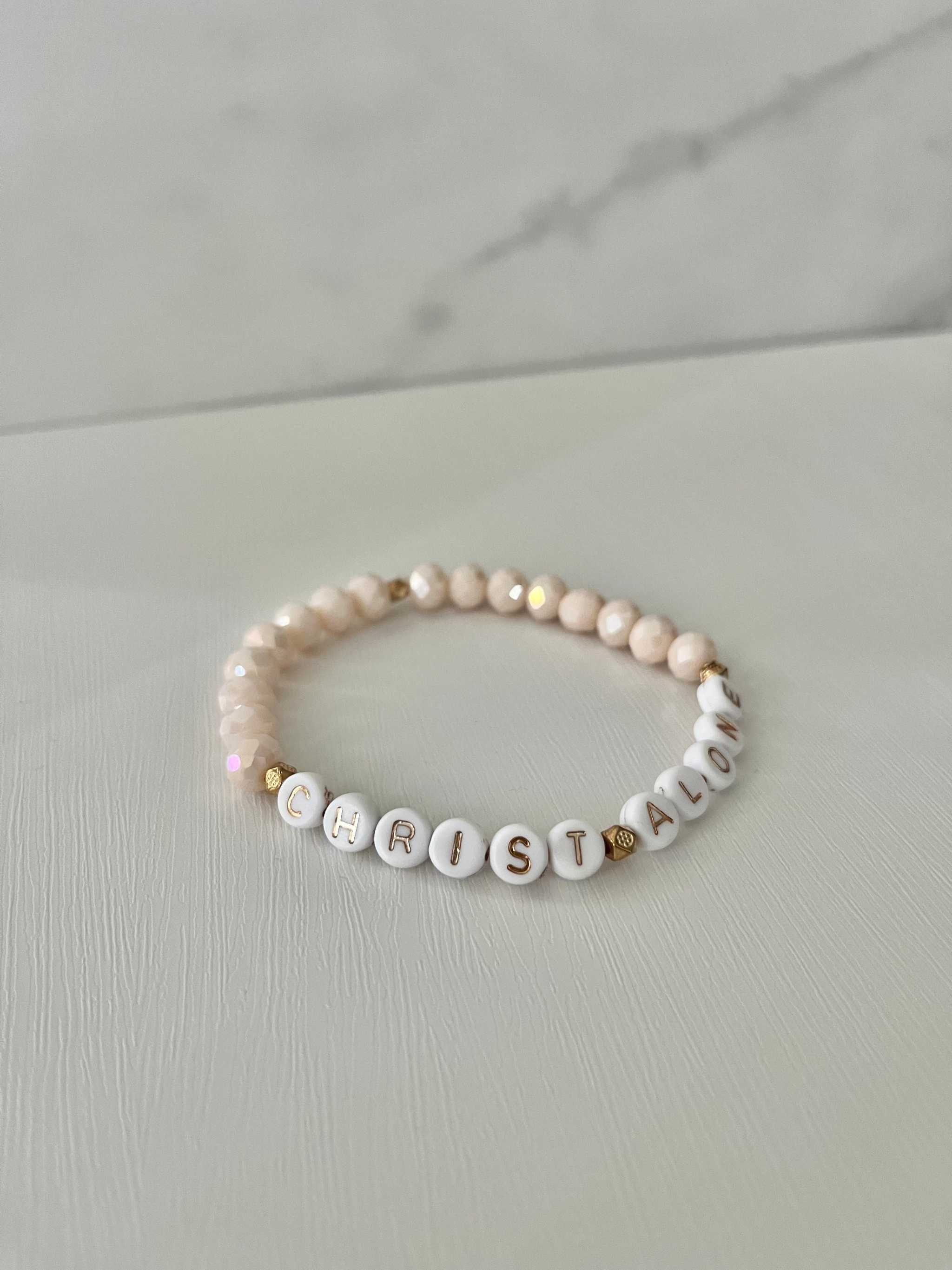 Peach-toned bead bracelet with “Christ Alone” letter beads