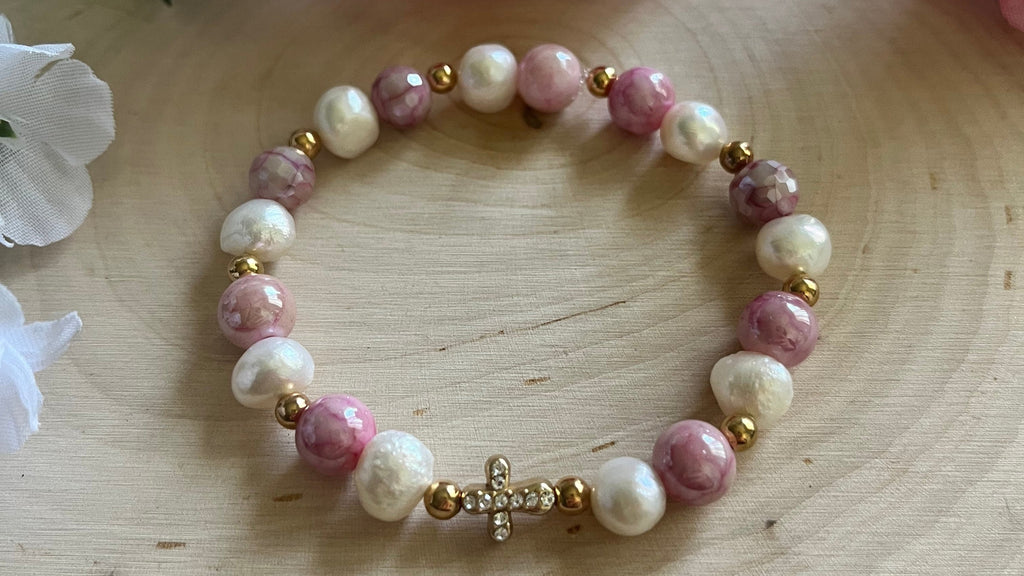 Pink and white pearl bead bracelet close-up with gold cross charm