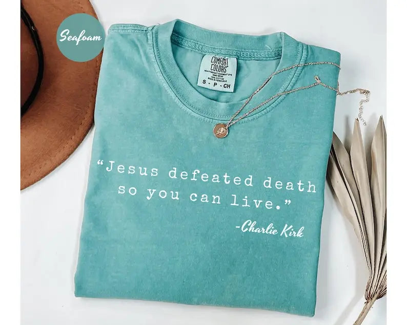 Teal crewneck T-shirt with 'Jesus defeated death' graphic and small pendant