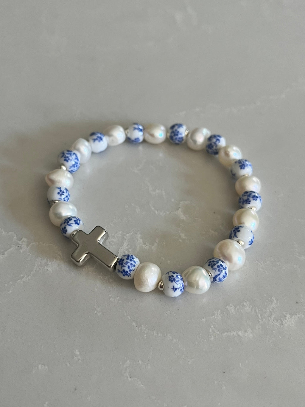 Pearl cross bracelet with blue speckled beads and white pearls, gold-tone cross centerpiece