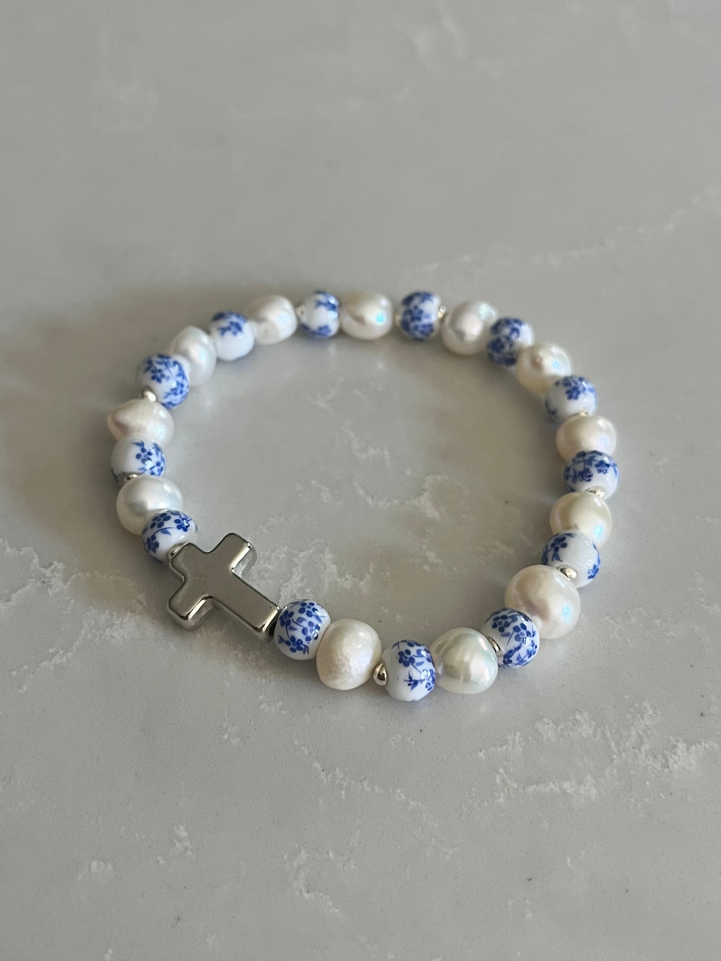 Pearl cross bracelet with blue speckled beads and white pearls, gold-tone cross centerpiece