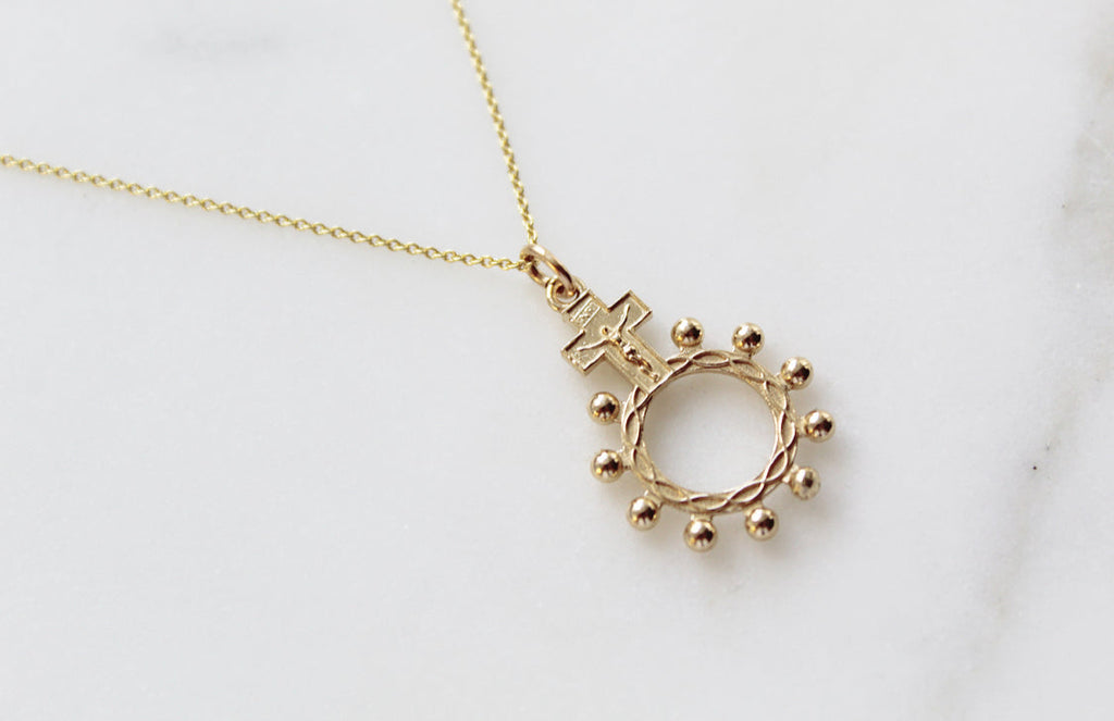14k gold rosary bead necklace with circular halo and small bead accents around a cross
