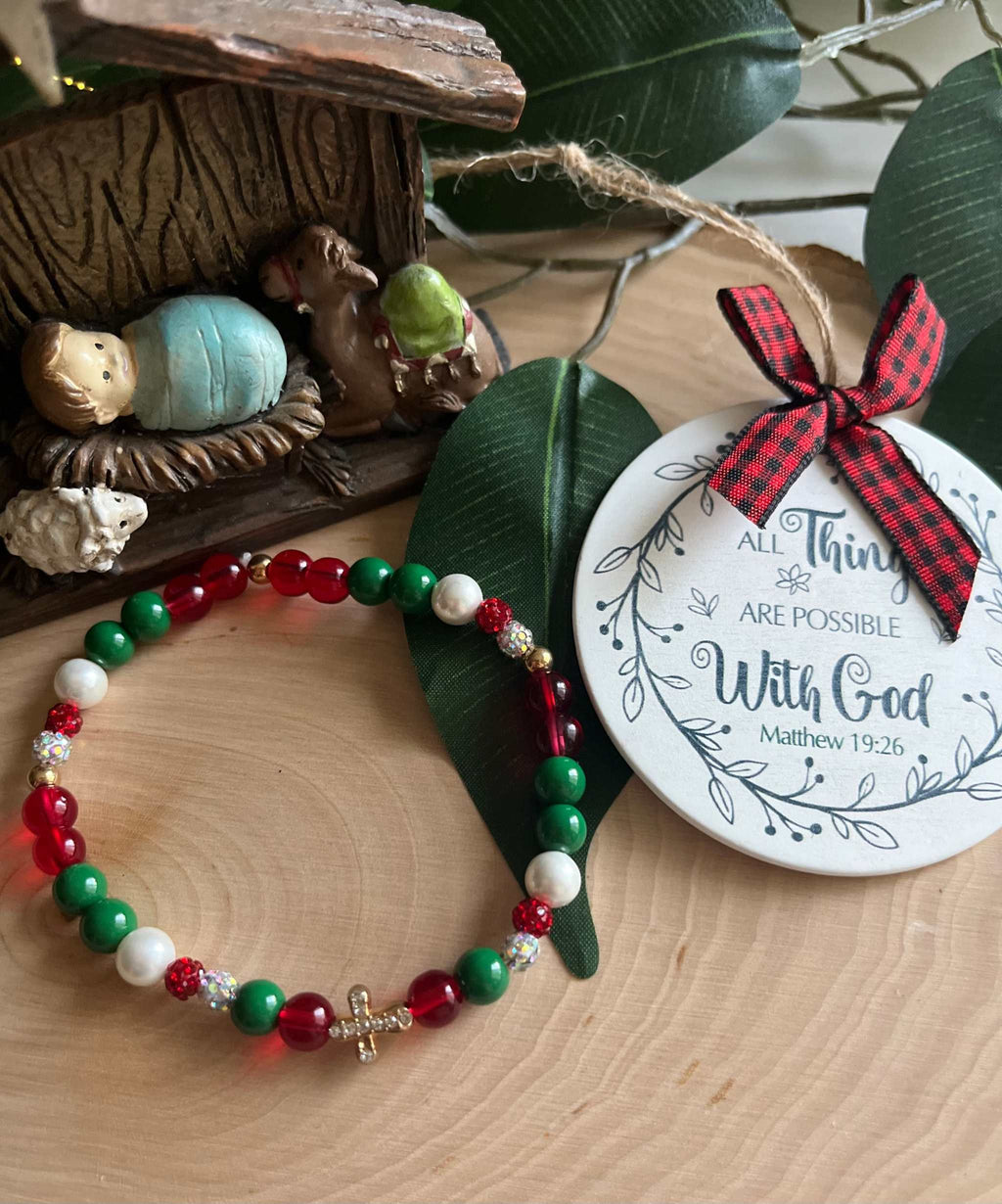 Beaded bracelet with red, green, and white beads and a small silver cross charm
