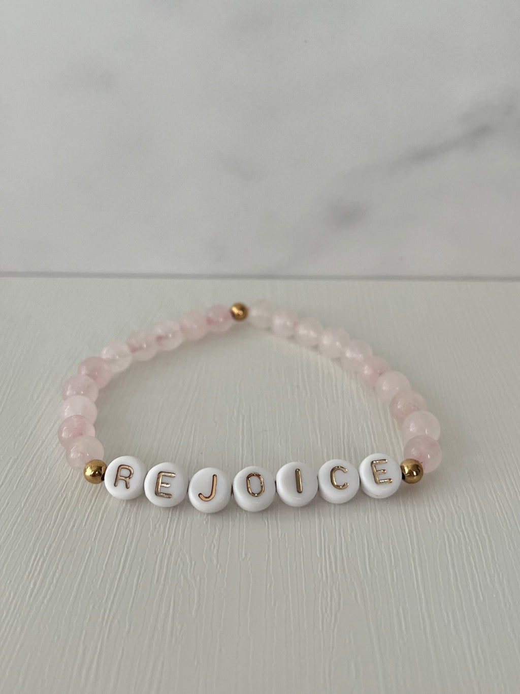 Pink beaded bracelet with REJOICE letter beads and small gold end beads