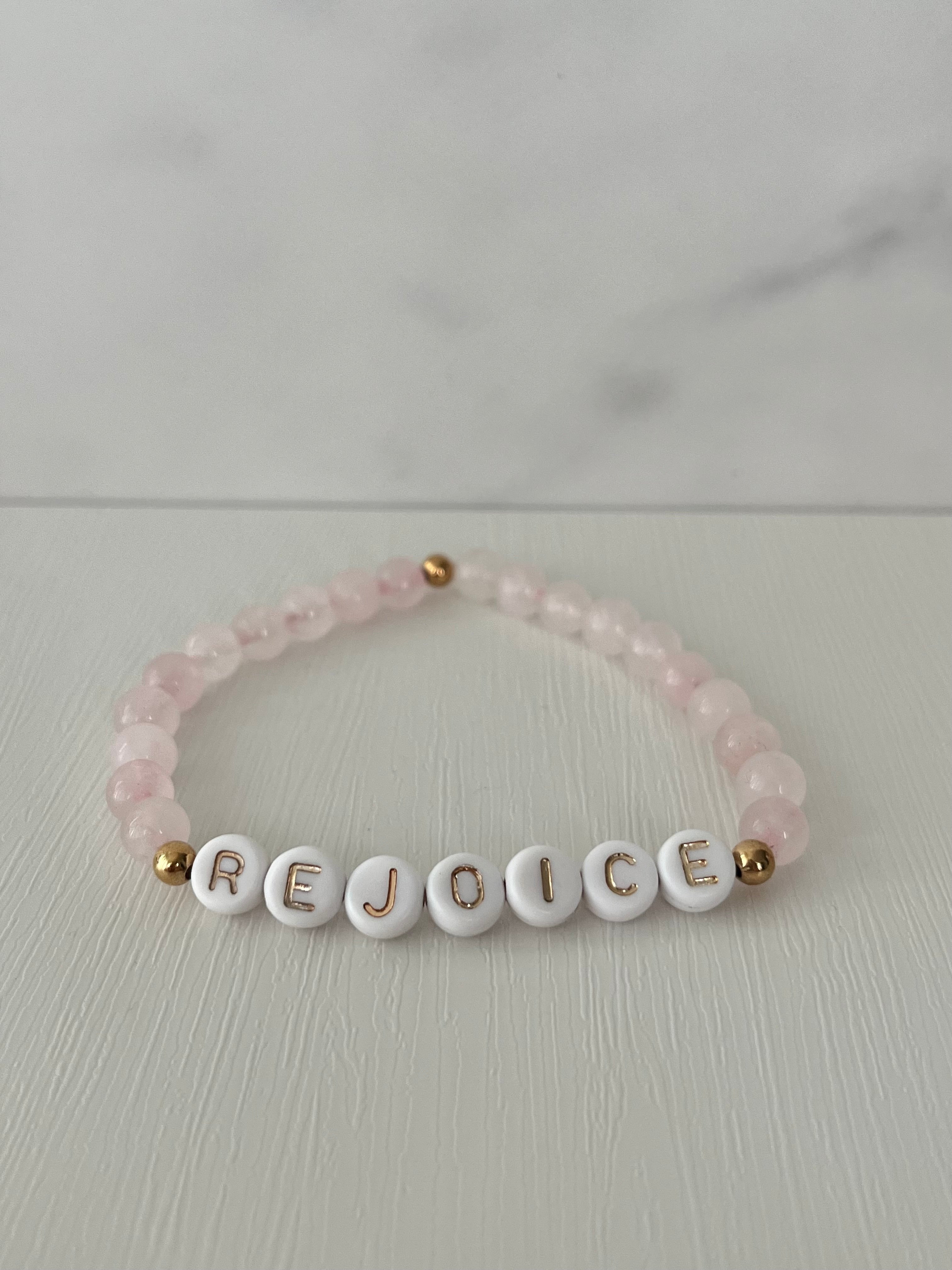 Pink beaded bracelet with REJOICE letter beads and small gold end beads