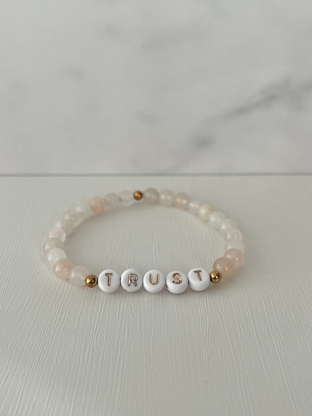 Cream beaded bracelet with TRUST letter beads and small gold accent beads