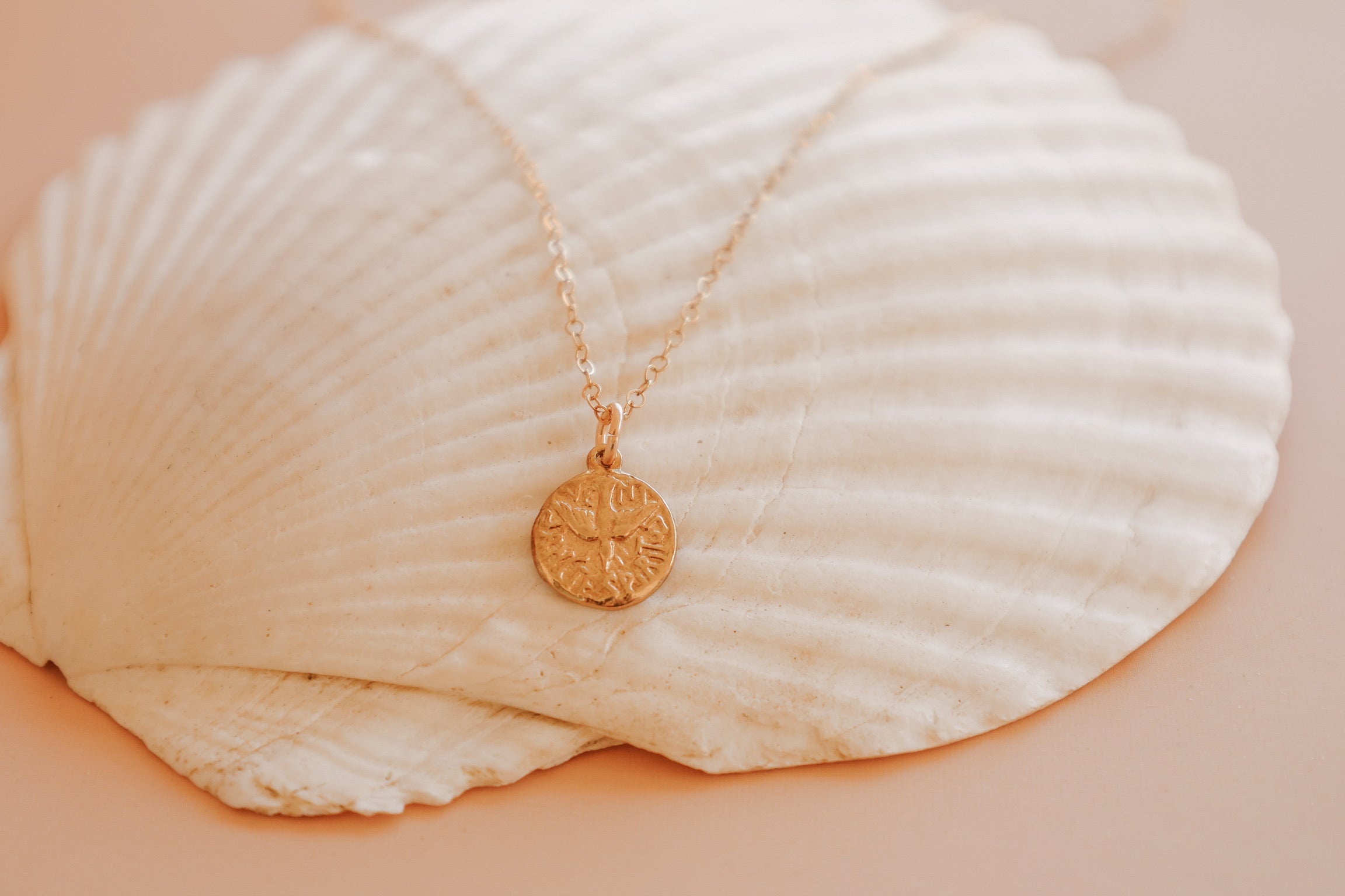 Gold pendant necklace with small round coin-style Holy Spirit charm on chain