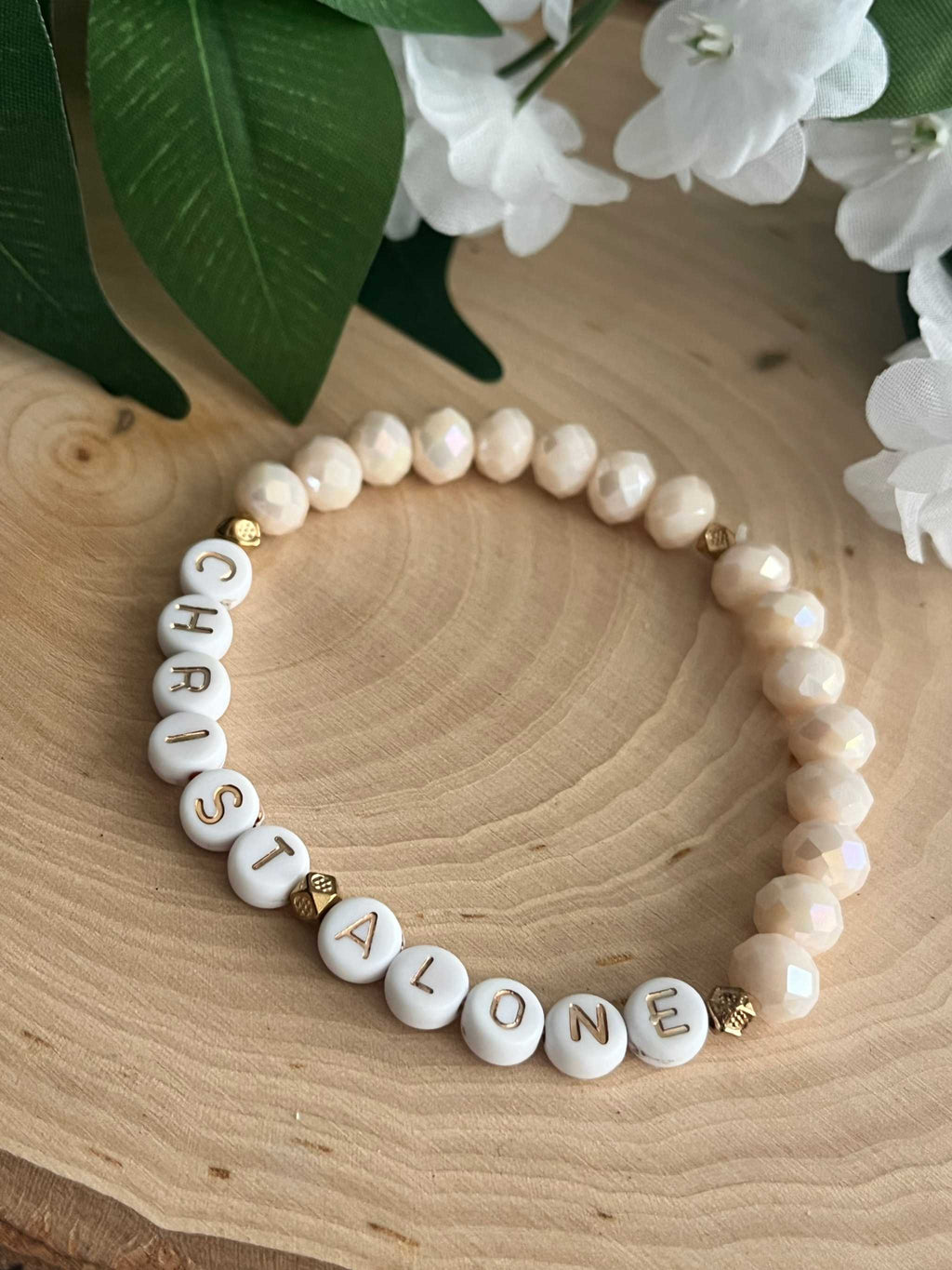 White bead bracelet with letter beads spelling "CHRIST ALONE" and gold accents
