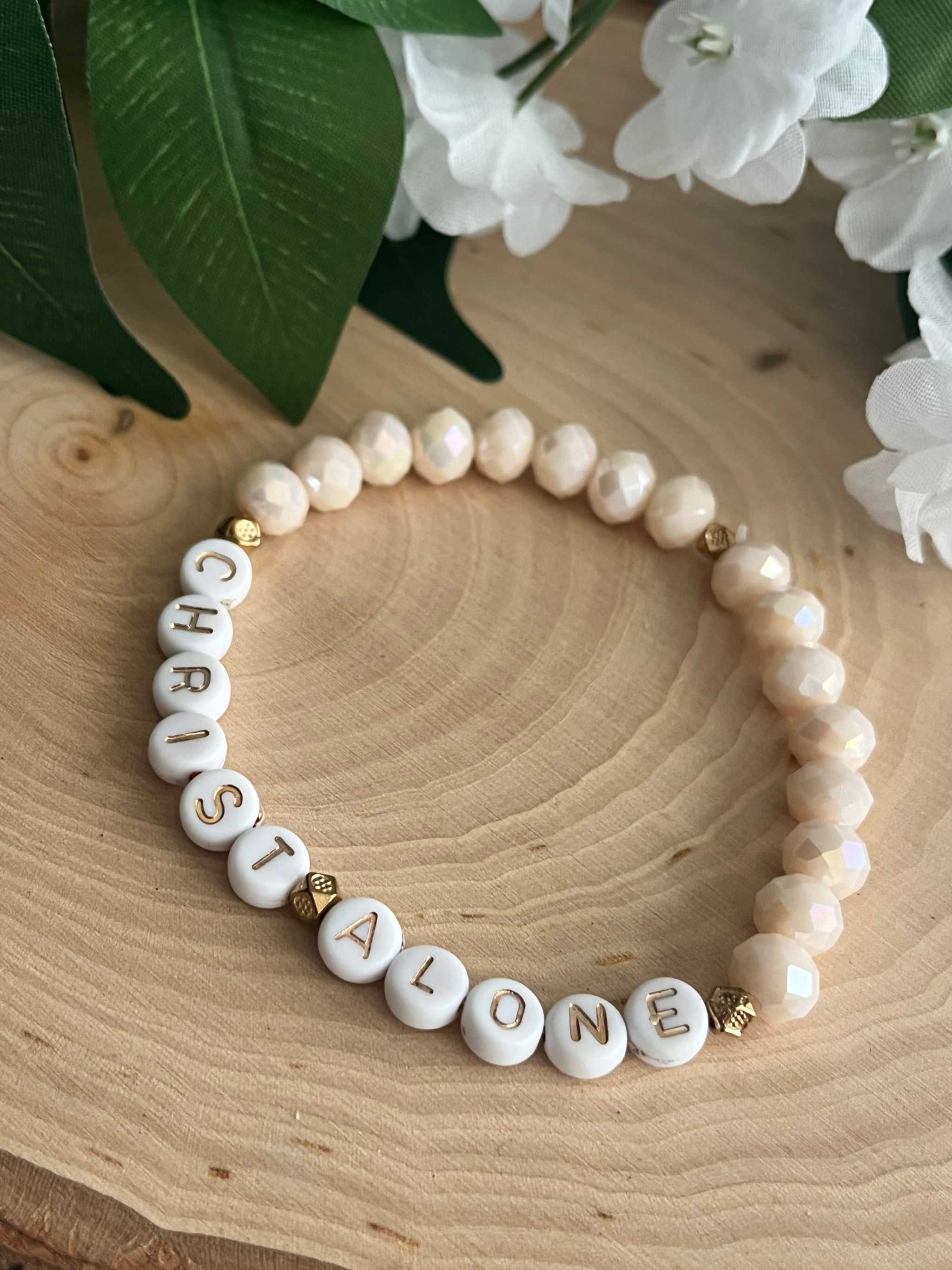 White bead bracelet with letter beads spelling "CHRIST ALONE" and gold accents
