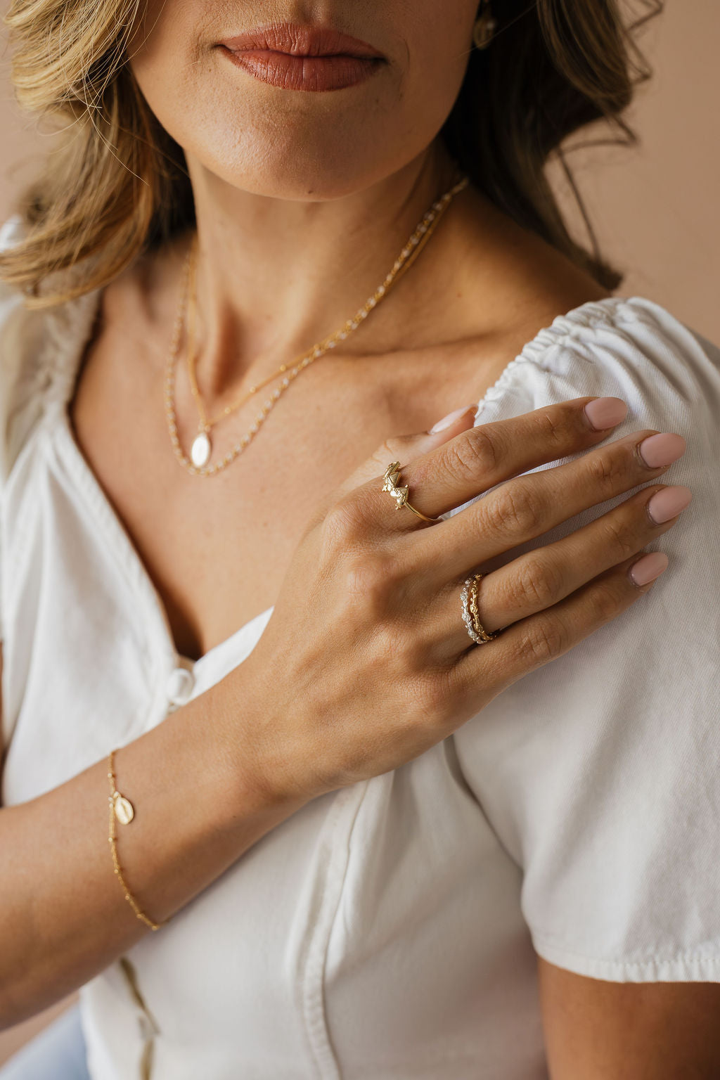 Gold chain necklace with oval medal pendant layered on a white blouse