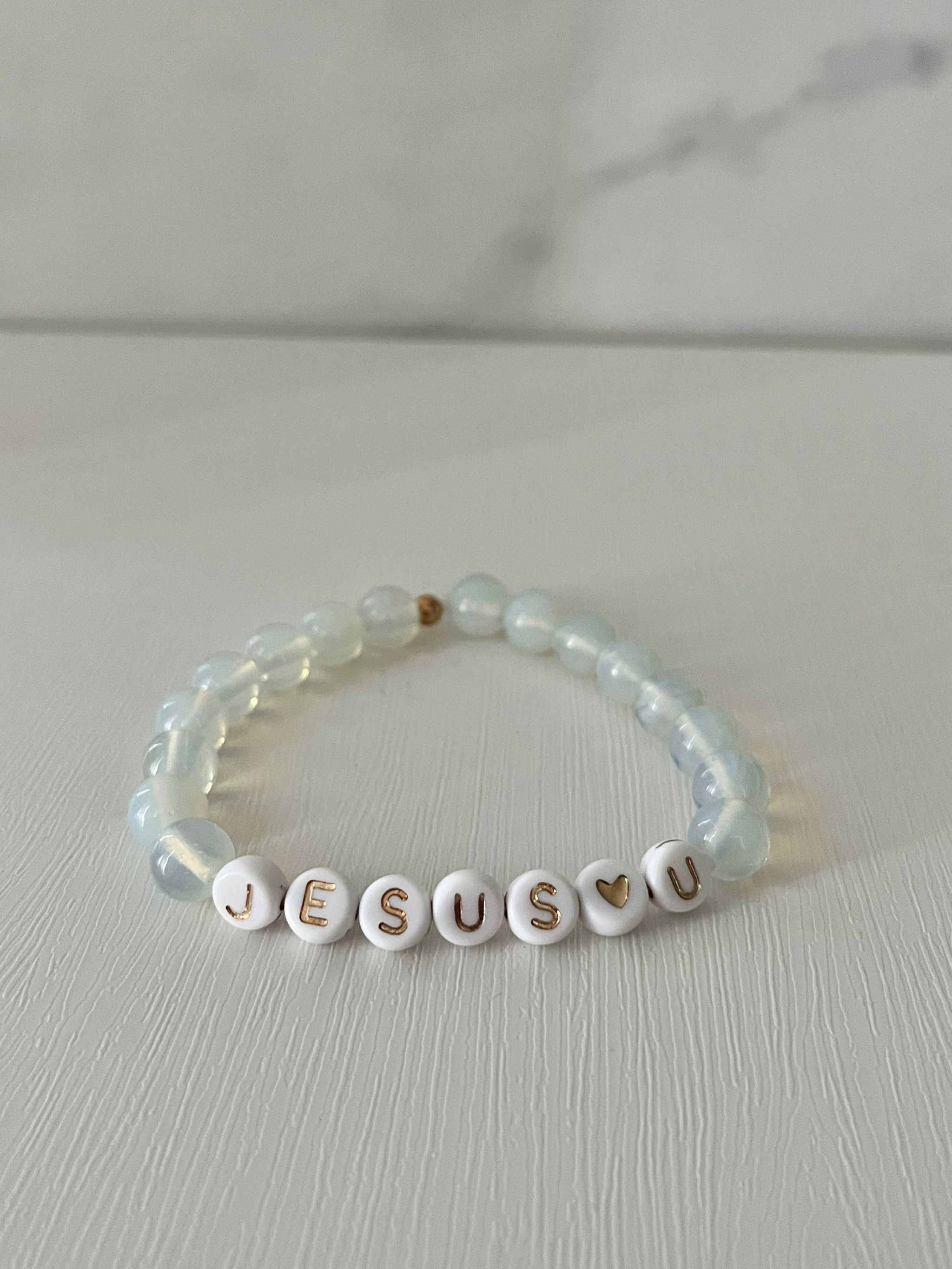 Clear bead bracelet with white letter beads spelling "JESUS U"