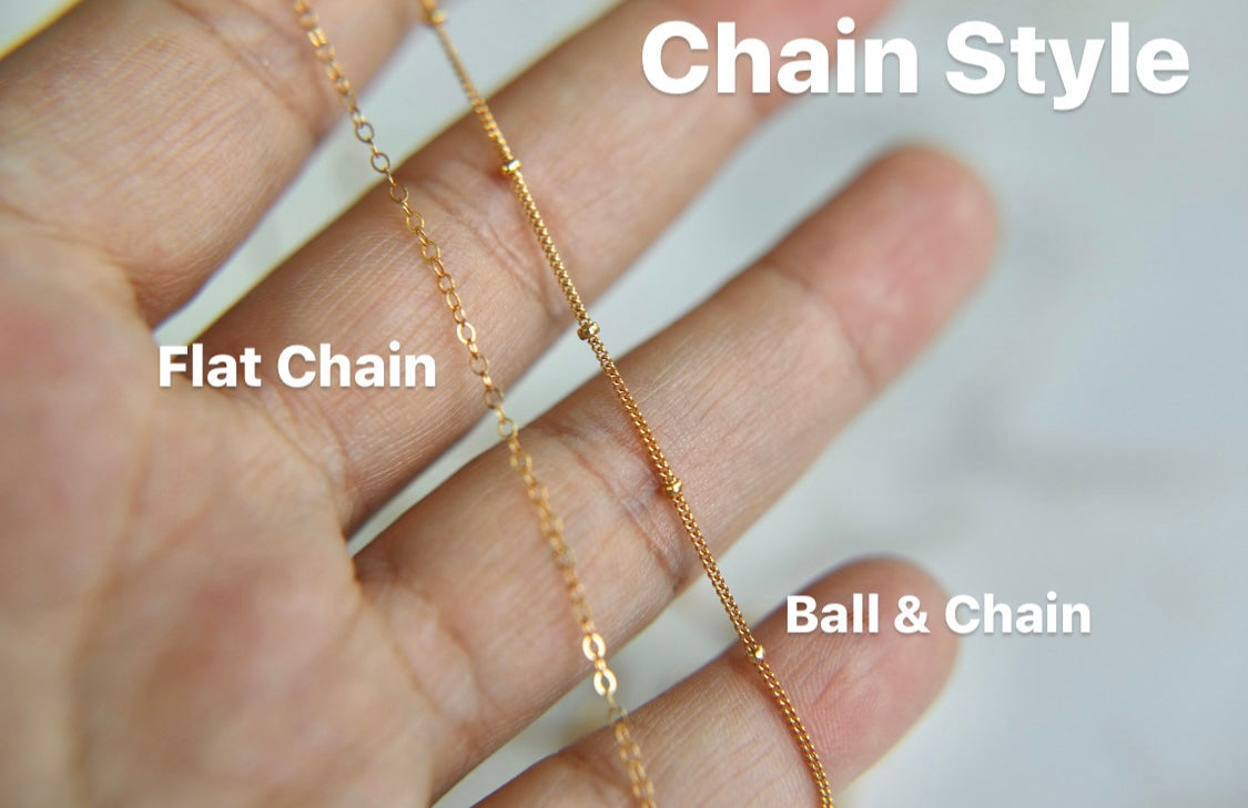 Gold-tone chain style necklaces with flat chain and ball-and-chain on palm