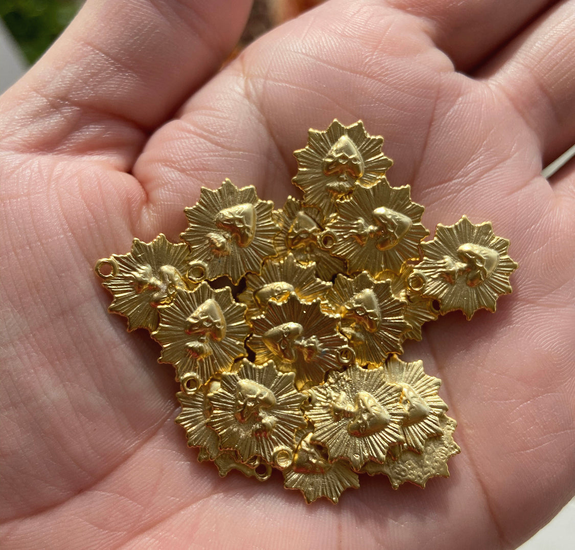 Gold-tone scalloped heart charm pieces in a hand