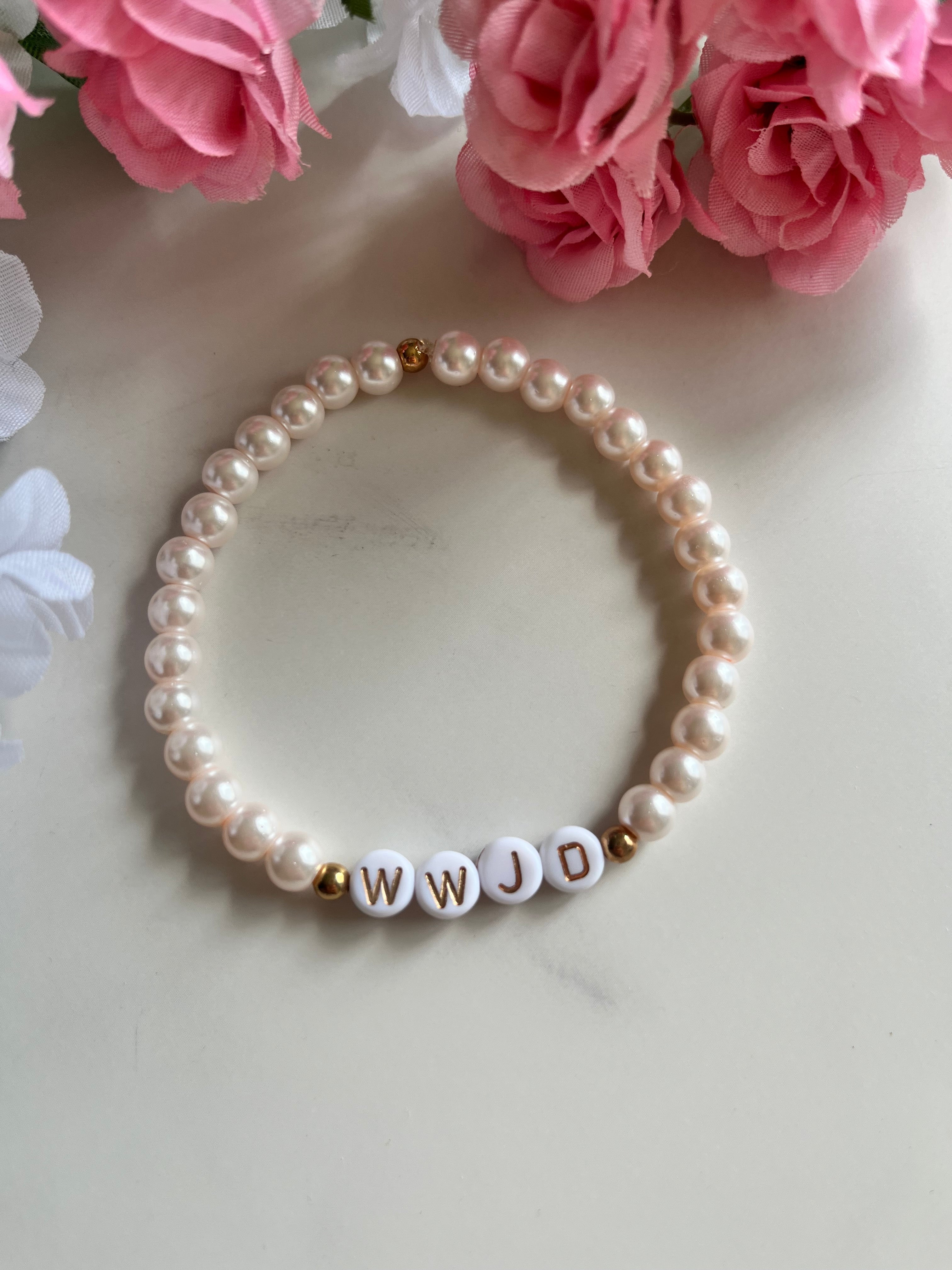 Pearl bead bracelet with small gold-letter beads spelling WWJD and white round pearls.