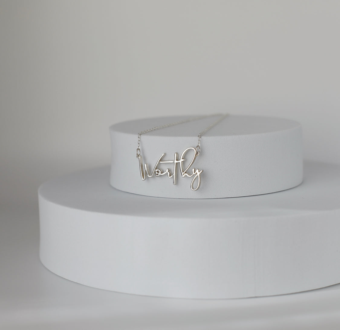 Sterling silver Worthy pendant necklace on pedestal