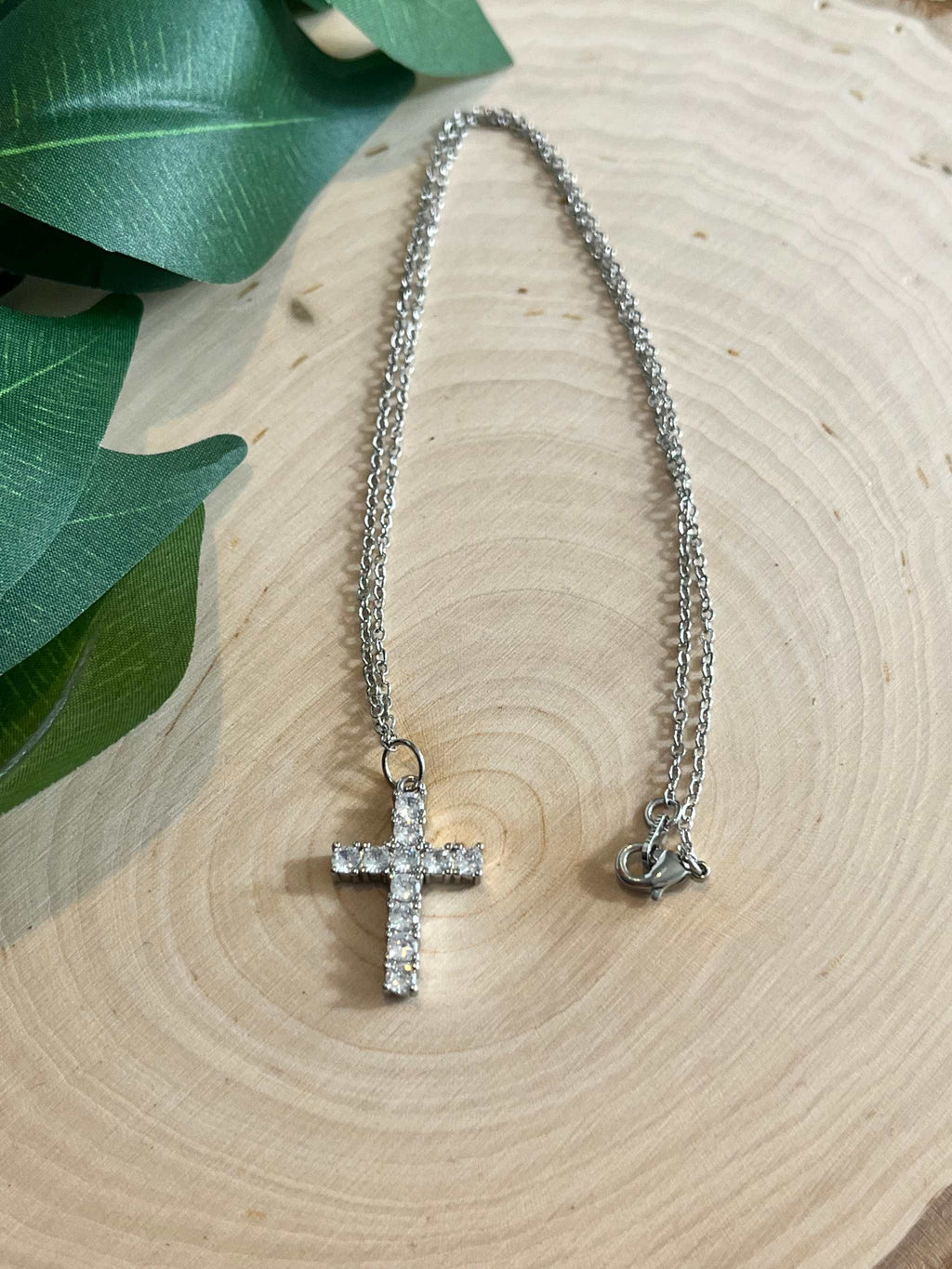 Silver cross pendant necklace with rhinestone cross, chain ends and clasp visible