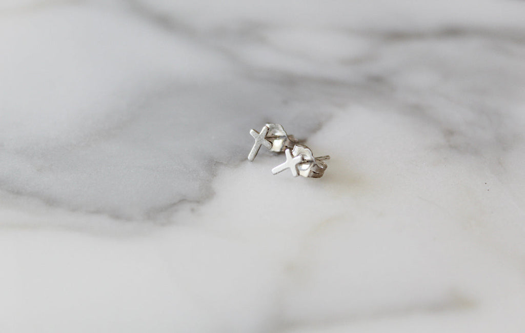 Sterling silver cross stud earrings set, two crosses on backing surface.