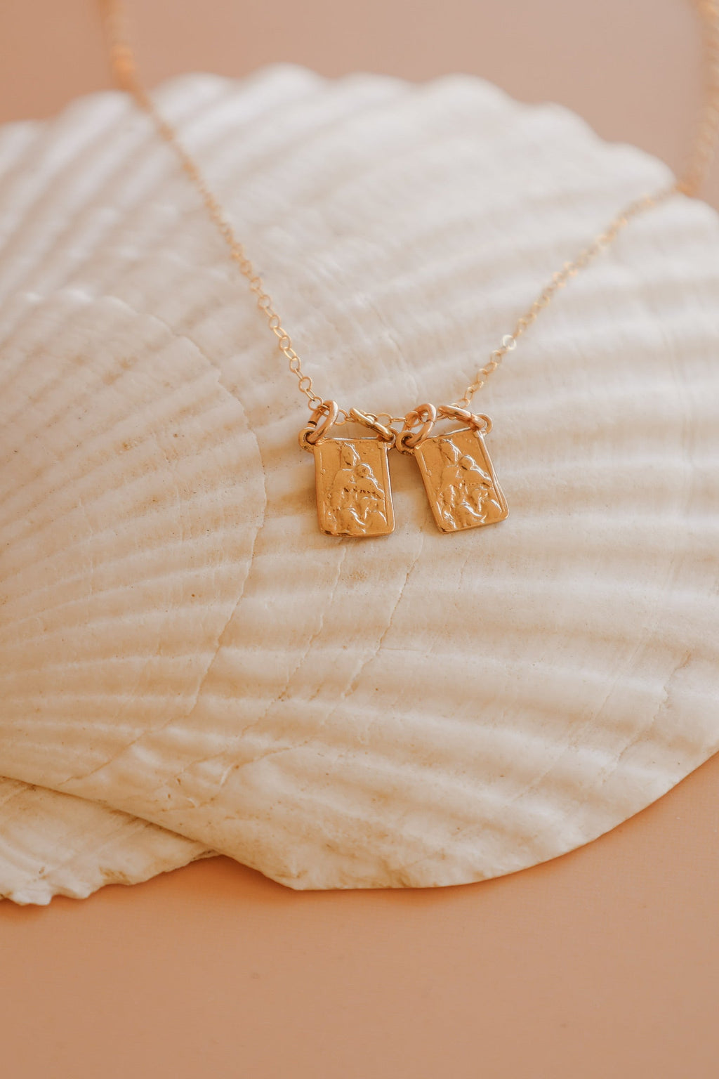 Scapular charm necklace with two small rectangular pendant charms on a gold chain