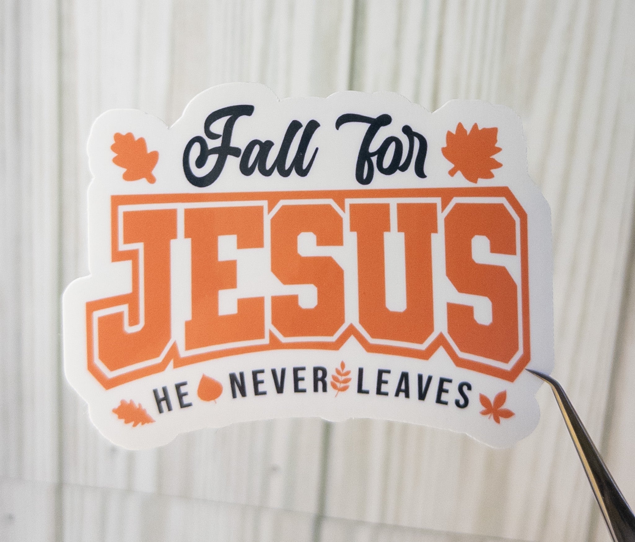 Fall for Jesus sticker: orange JESUS text, autumn leaves, and He never leaves