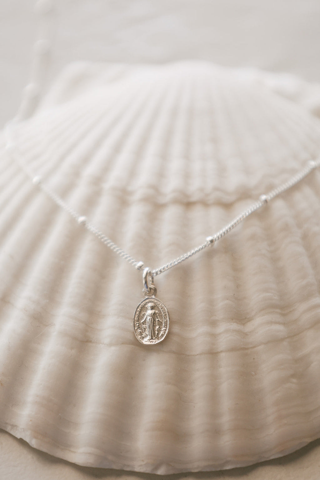 925 sterling silver oval medal pendant on fine chain, draped on fabric