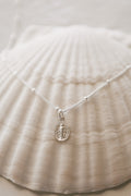 925 sterling silver oval medal pendant on fine chain, draped on fabric