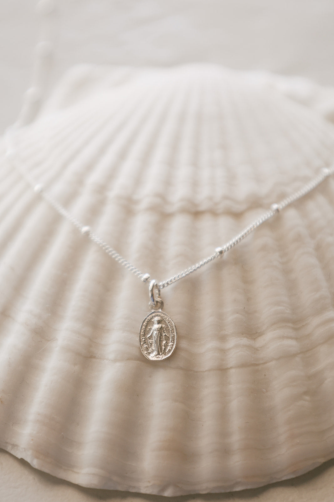 925 sterling silver oval medal pendant on fine chain, draped on fabric