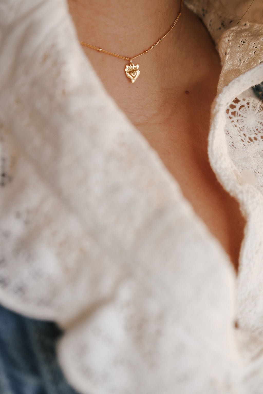 Gold heart charm necklace with small sacred heart pendant on a fine chain