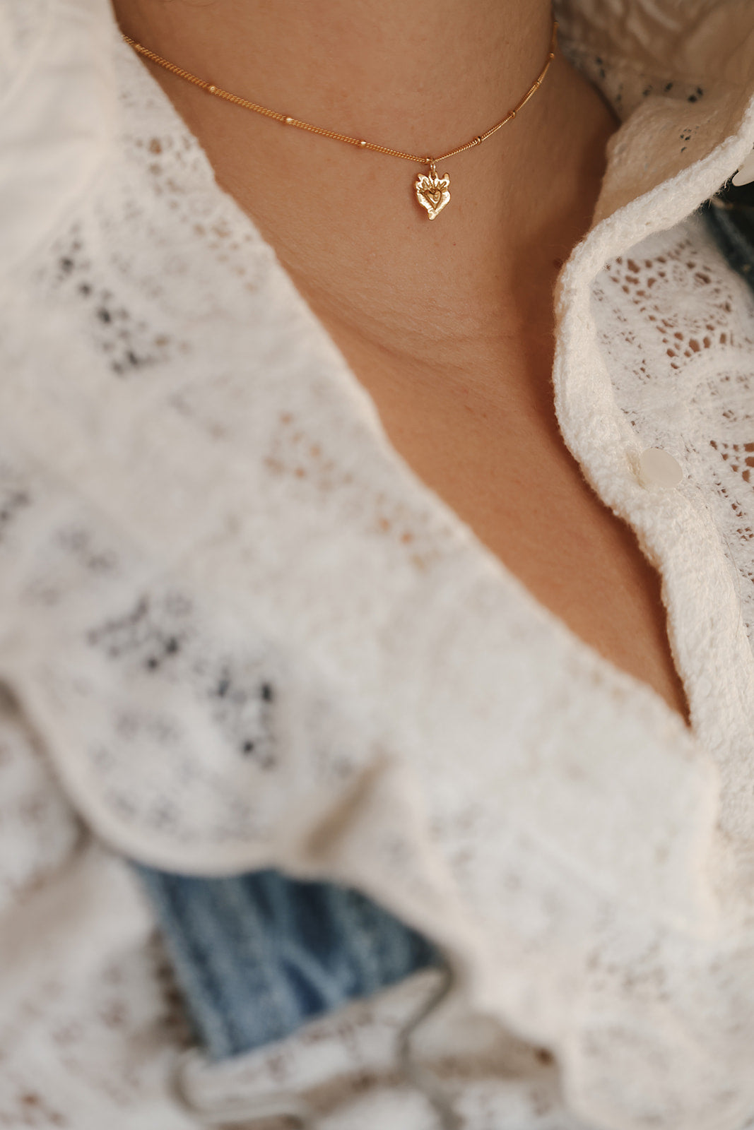 Close-up gold heart pendant necklace with tiny sacred-heart charm